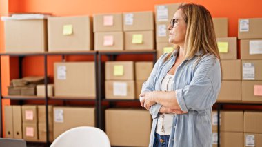 Orta yaşlı İspanyol kadın, iş adamı. Kollarını kavuşturup ofiste gülümsüyor.