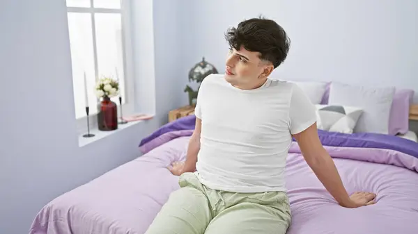 Młody Człowiek Siedzący Nowoczesnej Sypialni Kolorowym Łóżkiem Rozglądający Się Rozmysłem — Zdjęcie stockowe