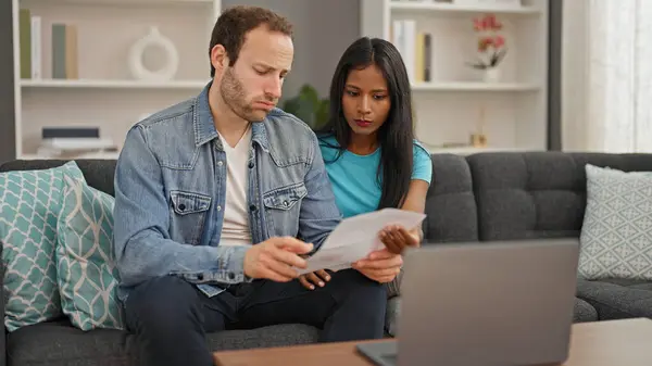 这对年轻漂亮的夫妇在家里用笔记本电脑看书 看起来很不高兴 — 图库照片