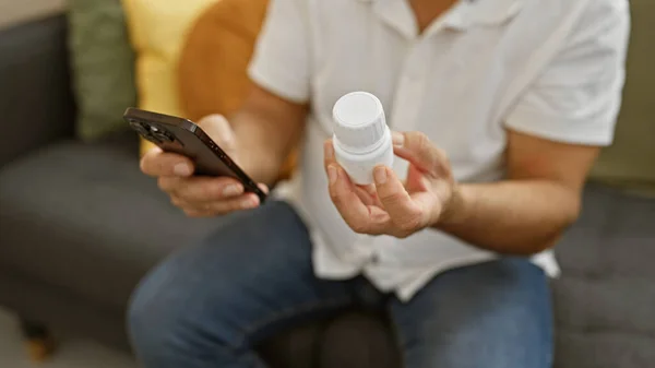 在一个现代化的客厅里拿着药品和智能手机的成熟男人 正在考虑如何重新开药方 — 图库照片