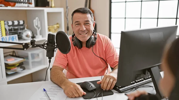Smiling confident man and woman radio interviewers engaged in live broadcast in a professional radio studio, staged for speaking, listening, and delivering news on air