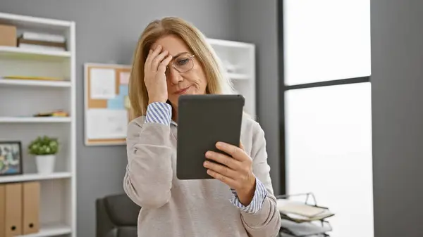 Worried Middle Aged Woman Office Looking Tablet Hand Forehead Evoking — Stock Photo, Image