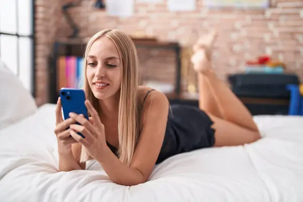 Νεαρή Ξανθιά Γυναίκα Που Χρησιμοποιεί Smartphone Ξαπλωμένη Στο Κρεβάτι Στο — Φωτογραφία Αρχείου