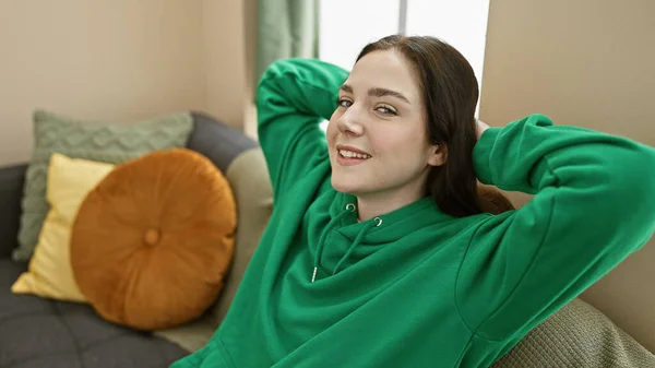 A relaxed young woman lounges at home on a cozy sofa, exuding casual comfort and a serene lifestyle.