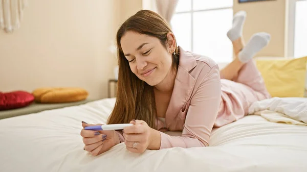 Uśmiechnięta Młoda Kobieta Leży Łóżku Testem Ciążowym Sugerując Oczekiwanie Radość — Zdjęcie stockowe