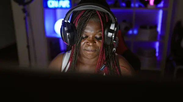 Passionate african american woman streamer bringing virtual magic into the night, streaming live game from her tech-rich gaming room