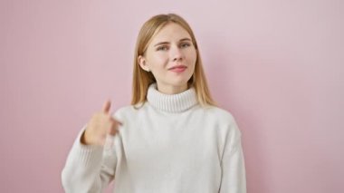 Sarışın güzel telefon jesti yapıyor, pembe izole edilmiş arka planda neşeyle sohbet ediyor. çarpıcı mavi gözleri gülümsüyor, barışçıl iletişim için anahtar kavram..