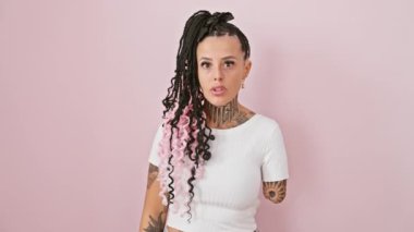 Ampüte İspanyol kadın pembe izole edilmiş arka plana şüpheyle bakıyor. İnançsız bir şekilde ağzı açık, alaycı bakışları gözlerinde..