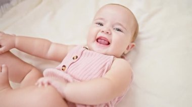 Evdeki değerli an, sevimli gülümseyen bebek, şirin kıyafetler giymiş, oturma odasındaki konforun keyfini çıkarıyor.