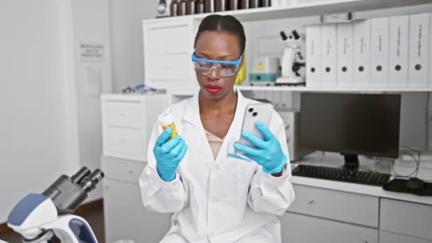 魅力的なアフリカ系アメリカ人女性科学者が研究室でスマートフォンで錠剤を分析し 画期的な医薬品研究に集約 — ストック動画