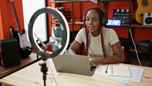 笑顔のアフリカ系アメリカ人女性記者放送 ラジオスタジオでビデオ通話中にヘッドフォンと話し プロのメディアとニュースインタビューの世界に没頭 — ストック動画
