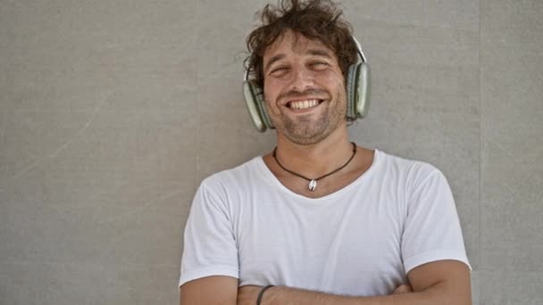 Lächelnder Junger Hispanischer Mann Mit Kopfhörern Posiert Selbstbewusst Vor Einer — Stockvideo