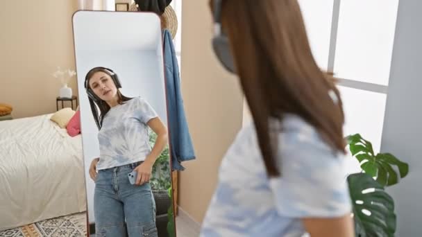 Eine Junge Frau Mit Kopfhörern Posiert Kokett Vor Einem Spiegel — Stockvideo