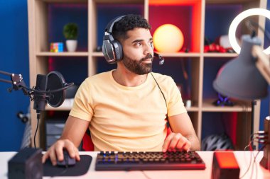 Sakallı İspanyol adam kulaklıkla video oyunu oynuyor. Yan tarafa bakıyor. Profil pozu veriyor.. 