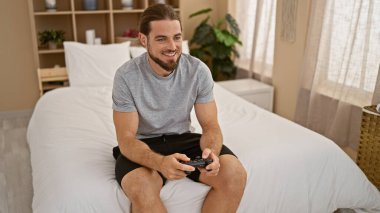 Yatak odasında video oyunu oynayan İspanyol genç adam.