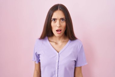 Pembe arka planda duran uzun saçlı genç İspanyol kadın şaşkınlık ve şaşkınlık dolu bir ifade, korku ve heyecan dolu bir yüz ifadesiyle dehşete düşmüş ve şok olmuştu.. 