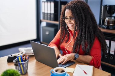 Ofiste çalışırken dizüstü bilgisayar kullanan Afrikalı Amerikalı iş kadını.