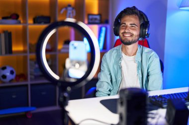 Dövmeleri olan, mutlu ve havalı bir gülüşü olan, akıllı telefonlu özel ders kaydı yaptıran genç İspanyol bir adam. şanslı kişi. 