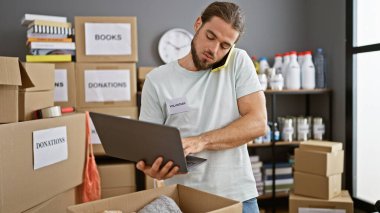 Genç İspanyol gönüllü yardım merkezinde bilgisayarla akıllı telefondan konuşuyor.