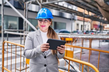 Genç, güzel İspanyol bir mimar sokakta dokunmatik ped kullanarak gülümsüyor.