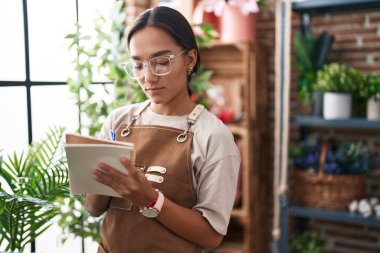 Çiçekçide deftere yazan güzel İspanyol bir çiçekçi kadın.