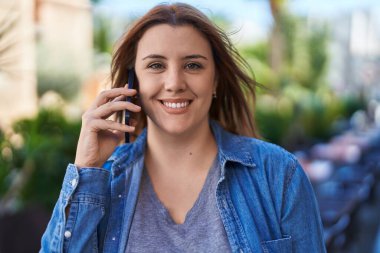 Genç, güzel, iri yarı, kendine güvenen bir kadın kahve dükkanının terasında akıllı telefondan konuşuyor.