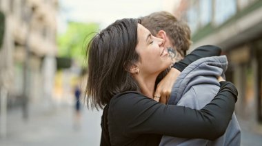 Güzel bir çift gülümsüyor. Sokakta birbirlerine sarılıyorlar.