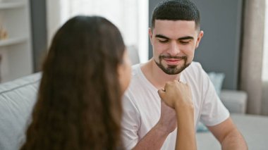 Çekici bir çift kanepede oturuyor, elleri siyam öpücüğüne kilitlenmiş, güzel bir evde mutluluktan uçuyor.