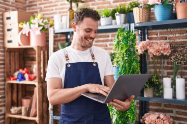 Çiçekçiye dizüstü bilgisayar kullanarak gülümseyen İspanyol bir çiçekçi.