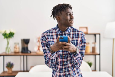 African american man using smartphone standing at home