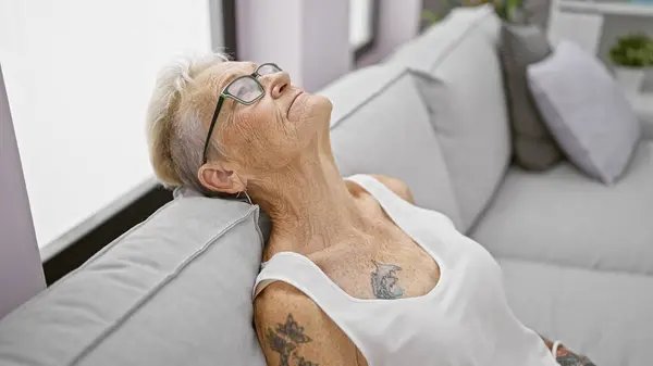 Yaşlı Gri Saçlı Rahatlamaya Sarılmış Bir Kadın Oturma Odasındaki Kanepede — Stok fotoğraf