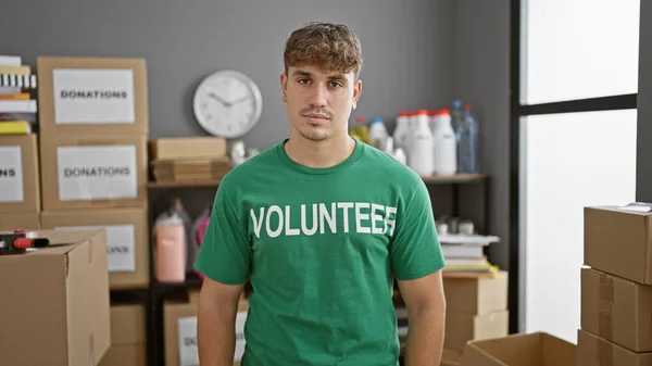 Handsome young hispanic man volunteers at charity center, his serious face reflecting the gravity of work in community service