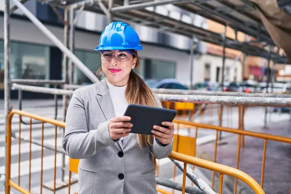 Genç, güzel İspanyol bir mimar sokakta dokunmatik ped kullanarak gülümsüyor.
