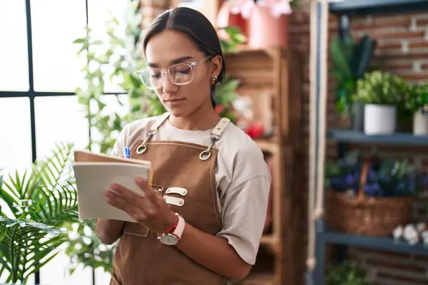 Çiçekçide deftere yazan güzel İspanyol bir çiçekçi kadın.