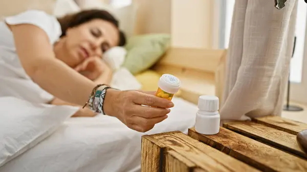 西班牙女人躺在床上 躺在舒适的卧室里 手里拿着药 — 图库照片