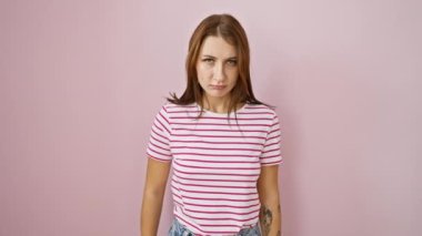 Çizgili tişörtlü öfkeli, genç esmer kız, gözle görülür bir şekilde şiddetle tehdit ediyor - hayali bıçakla boğazını kesiyor, pembe arka plana karşı bariz agresif bir duruşu var..