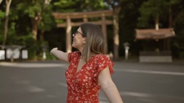 Neşeli İspanyol kadın kollarını açmış gülümsüyor, Meiji tapınağına bakıyor, kendine güvenini ve mutluluğunu gösteriyor.