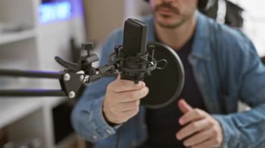 Kulaklıklı adam modern kayıt stüdyosunda mikrofonu ayarlıyor.