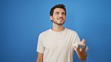 Yakışıklı İspanyol bir adam gülümsüyor ve mavi bir duvara karşı araba anahtarı tutuyor..