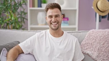 Modern bir oturma odasında gülümseyen yakışıklı bir adam..