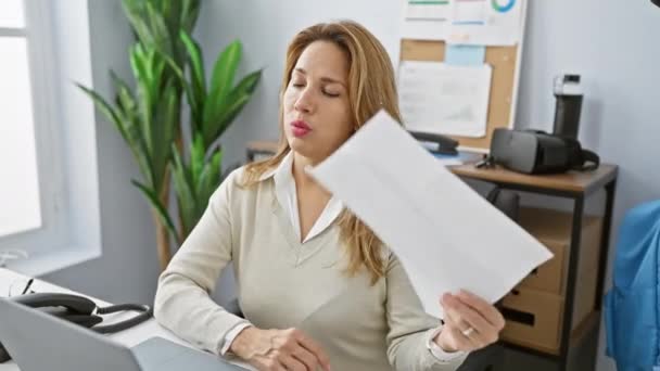 Hispanic Woman Fanning Herself Papers Modern Office Setting Expressing Discomfort — Stock Video