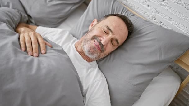 白发苍苍的中年男人在舒适的卧室床上欢快地伸展着双臂醒来 享受着舒适的室内早晨的舒适 — 图库视频影像