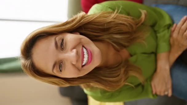 Улыбающаяся Латиноамериканка Зеленой Рубашке Комфортно Сидит Уютной Гостиной Вызывая Тепло — стоковое видео