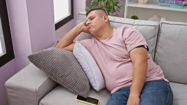 快乐的年轻拉丁裔男人在智能手机上愉快地发短信 舒适地坐在沙发上 一幅充满高科技气息的室内快乐的画像 — 图库视频影像