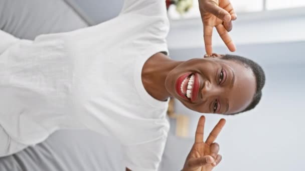 Χαρούμενη Αφροαμερικάνα Που Χαλαρώνει Στην Κρεβατοκάμαρα Δείχνοντας Σύμβολο Της Ειρήνης — Αρχείο Βίντεο