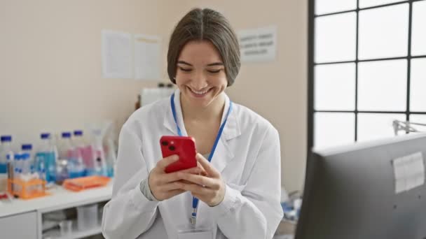 Uśmiechnięta Młoda Kobieta Fartuchu Laboratoryjnym Używająca Smartfona Laboratorium Medycznym — Wideo stockowe