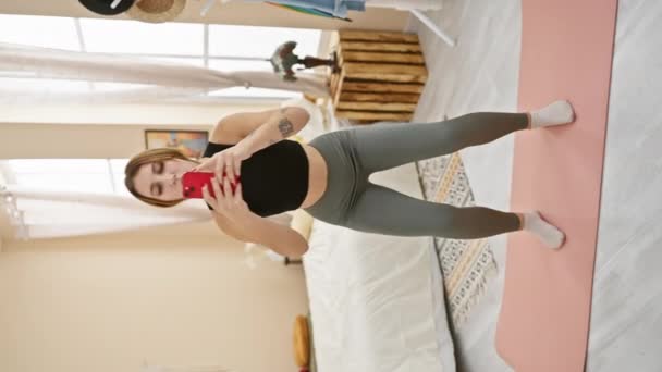 Ung Kvinna Sportkläder Tar Selfie Ett Ljust Sovrum Med Yogamatta — Stockvideo
