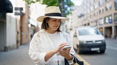 Stockholm sokaklarında akıllı telefon kullanan güzel bir İspanyol kadın.