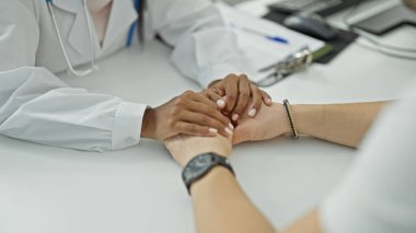 Doktor ve hasta klinikte el ele oturuyorlar.