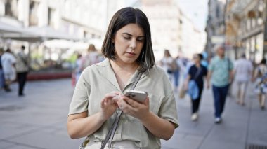Genç ve güzel İspanyol kadın Viyana sokaklarında akıllı telefon kullanıyor.